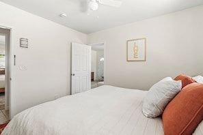 A bedroom with a bed, pillows, a ceiling fan, a door, and a framed picture on the wall. - Resort-Style Desert Retreat with Huge Pool, Spa city id 069562 City ID # 069562 (Palm Springs)