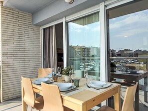 A dining area with a table set for four, large windows, and a view of the cityscape. - Sonnige Ferien by Interhome (St Antoni de Calonge)