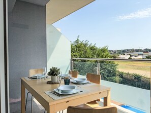 A dining table set on a balcony with a view of a swimming pool and distant buildings. - Sonnige Ferien by Interhome (St Antoni de Calonge)