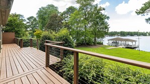 A wooden deck with a railing, a grassy area, and a lake view with a dock and pavilion. - Lakefront 3-bedroom house on Poe Creek at Lake Gaston. Bring your boat! (Littleton)