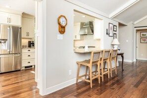 A kitchen with wooden cabinets, a stainless steel refrigerator, and a dining area with a table and chairs. - Lakefront 3-bedroom house on Poe Creek at Lake Gaston. Bring your boat! (Littleton)