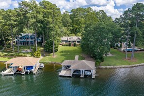 A lakeside property with two docked boats, a large house, and a well-maintained lawn.