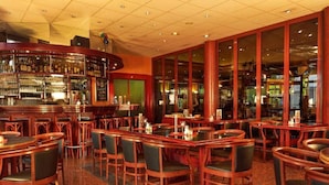 Eine Bar mit einer gebogenen Theke, mehreren Sitzgelegenheiten und Stühlen.