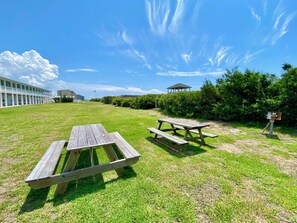A picnic area with wooden benches and a gazebo in the background. - Cozy studio condo with AC, pool and direct beach access (Atlantic Beach)