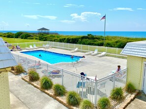 A swimming pool with a white fence, lounge chairs, and an American flag. - Cozy studio condo with AC, pool and direct beach access (Atlantic Beach)