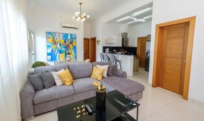 A modern living room with a grey sofa, a coffee table, and a painting on the wall. - Fabulous 2-bedroom apartment in Bella Vista, Santo Domingo (Santo Domingo)