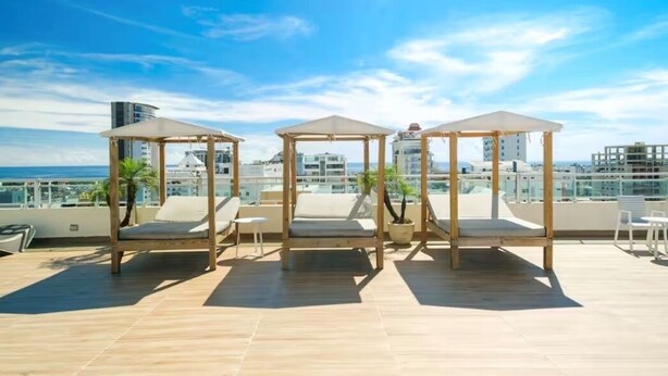 A rooftop terrace with three wooden gazebos, each with a cushioned seat and a potted plant. - Fabulous 2-bedroom apartment in Bella Vista, Santo Domingo (Santo Domingo)