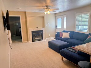 Ein Wohnzimmer mit Kamin, Deckenventilator und einer Couch.