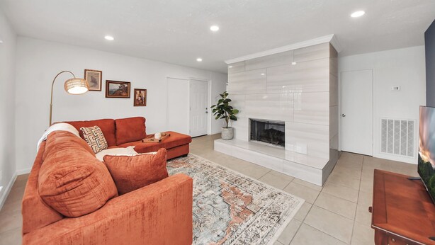 A modern living room with a sectional sofa, a fireplace, and a large TV. - Chic & Cozy Home, Perfect for Work + Weekend stays, Near Main Highways (Houston)