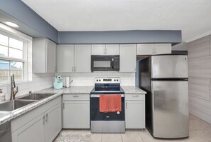 Eine moderne Küche mit grauen Schränken, einem Edelstahlkühlschrank, einer Mikrowelle und einem Backofen.