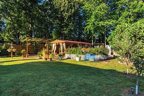 A garden with a wooden pergola, potted plants, and a blue bench. - Cozy 2-bedroom house in peaceful Woodbridge with AC (Woodbridge)