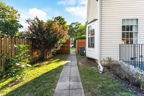 A narrow concrete pathway leading to a house with a wooden fence on one side and a metal fence on the other. - Cozy 2-bedroom house in peaceful Woodbridge with AC (Woodbridge)