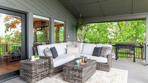 Un espace extérieur aménagé, abrité et doté d’un canapé d’angle, de poufs en osier et d’un barbecue.