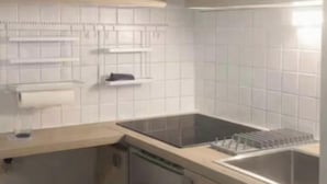A kitchen with white cabinets, a dishwasher, and a trash bin.