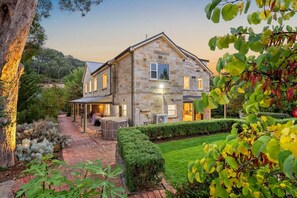 Une maison en pierre dotée d’une terrasse, d’un jacuzzi et d’un jardin bien entretenu.