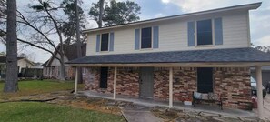 A two-story house with a brick facade and a covered porch. - Willowbrook Haven 2 Bed 2 Bath Townhome Apt. with Private Patio (Houston)