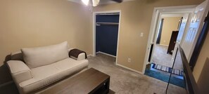 A living room with a sofa, a coffee table, and a door leading to another room. - Willowbrook Haven 2 Bed 2 Bath Townhome Apt. with Private Patio (Houston)