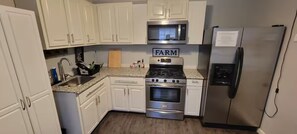 A kitchen with white cabinets, a stainless steel refrigerator, a microwave, and a stove. - Willowbrook Haven 2 Bed 2 Bath Townhome Apt. with Private Patio (Houston)