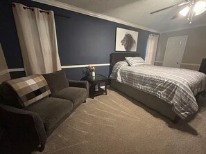 Ein Schlafzimmer mit Bett, Sofa, Nachttisch und Deckenventilator.