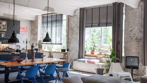 A spacious living area with a dining table, blue chairs, a sofa, and a TV. - STORAGE LOFT APARTMENT URBAN (Berlin)