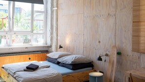 A room with a wooden bed, a window with a view, a small round table, and a wooden wall. - STORAGE LOFT APARTMENT URBAN (Berlin)