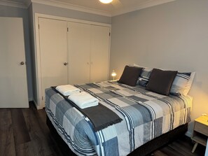 A neatly made bed with a striped bedspread and pillows, a bedside lamp, and a wardrobe with a door.