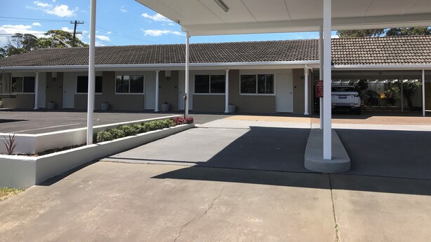 A motel with a covered parking area, a white exterior, and a tiled roof. - 2 Bedroom Apartment located in the heart of Ulladulla. (Ulladulla)