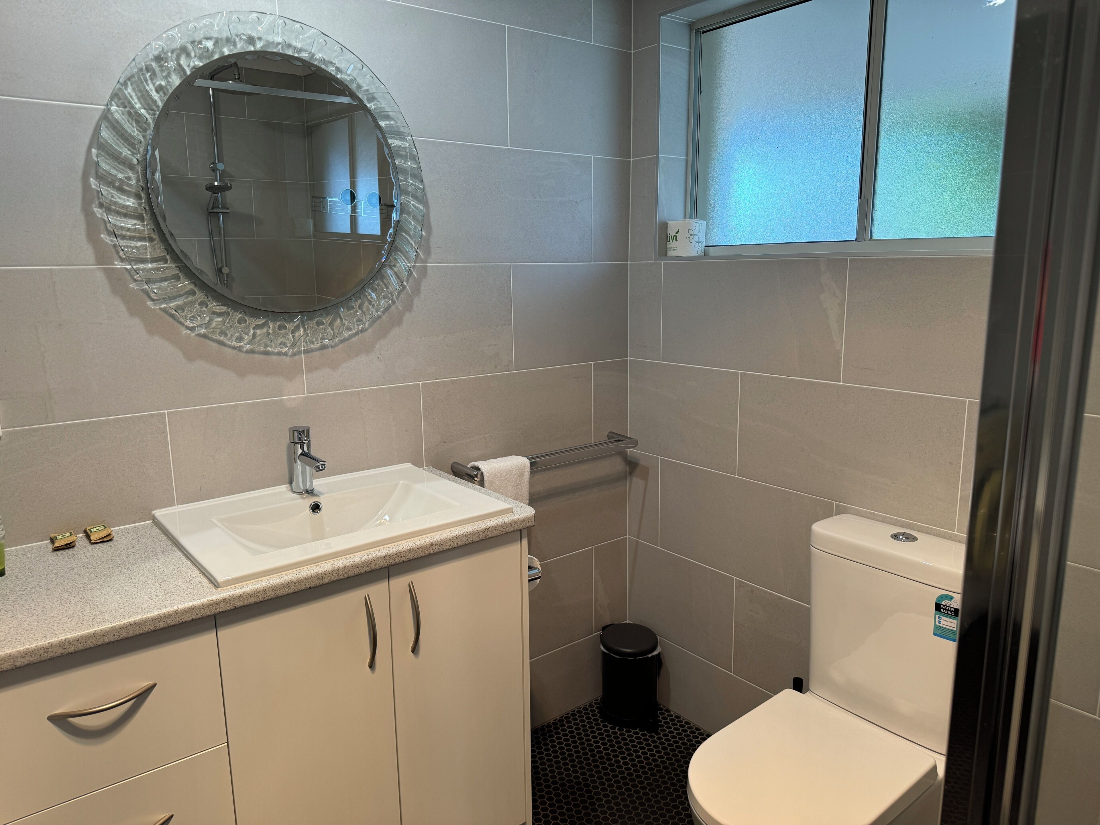 Een badkamer met een wastafel, toilet en spiegel.
