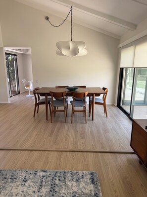 Ein stilvoller Essbereich mit Holztisch und -stühlen, einer Hängeleuchte und Blick durch ein großes Fenster.