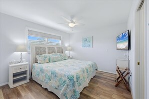 A bedroom with a bed, nightstands, a ceiling fan, a window, and a wall-mounted TV. - 4BR Gulf-view pool home on Palm Island, sleeps 10, Boat Dock (Placida)