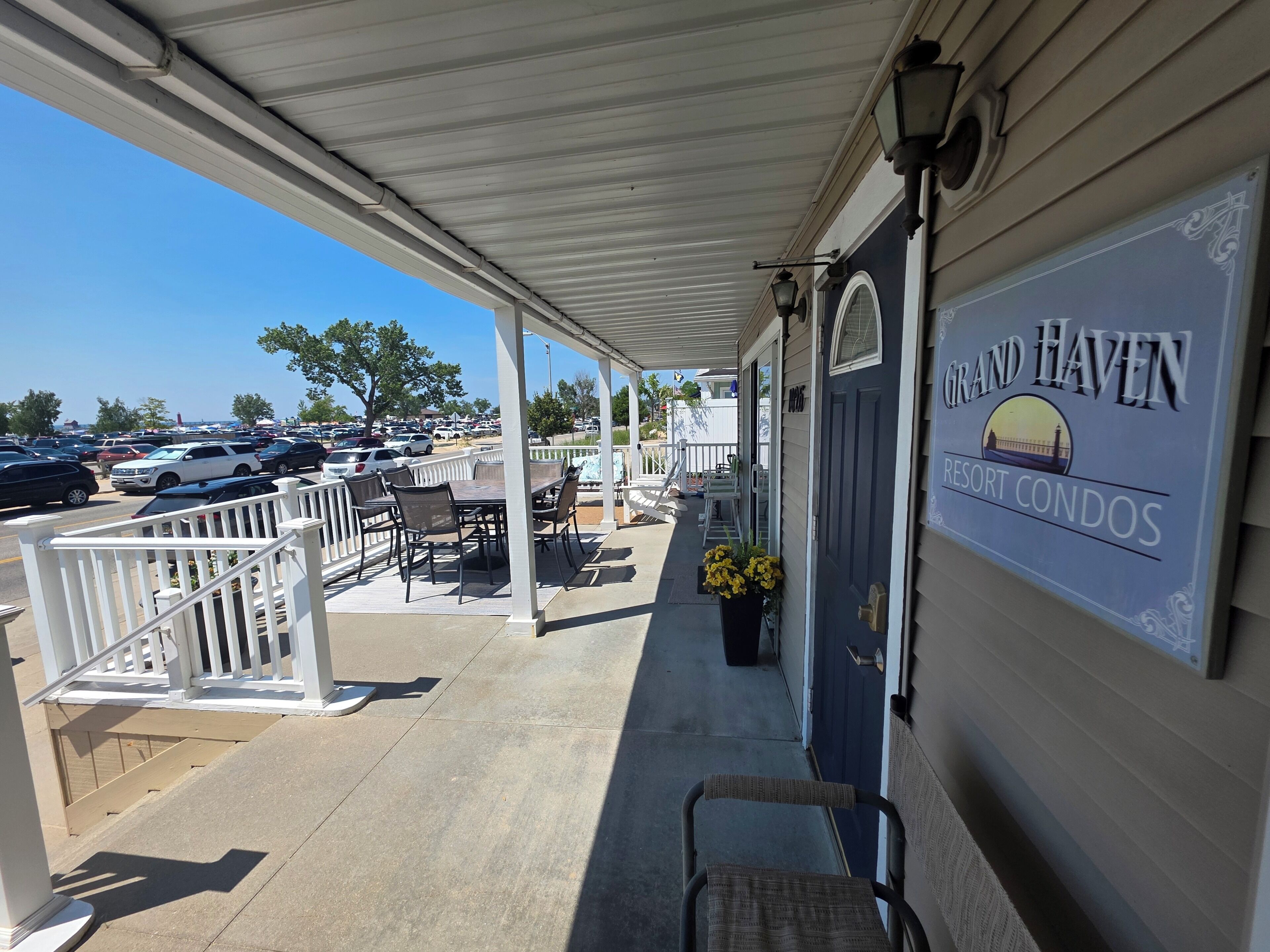 A covered porch with outdoor seating, a sign for Grand Haven Resort Condos, and a view of a parking lot.