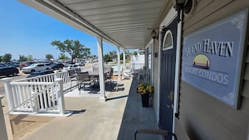 A covered porch with outdoor seating, a sign for Grand Haven Resort Condos, and a view of a parking lot.