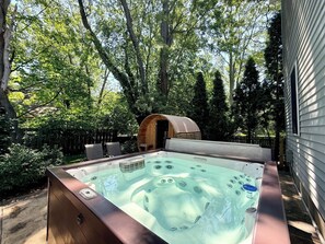 A hot tub in a backyard with a wooden structure and trees. - Whimsy Wild: Walk to Downtown Saugatuck, Sauna, Hot Tub, Screen Porch, Fire Pit (Saugatuck)