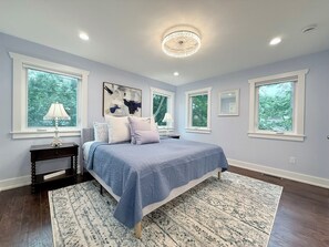 A bedroom with a bed, a nightstand, a window, and a ceiling fan. - Whimsy Wild: Walk to Downtown Saugatuck, Sauna, Hot Tub, Screen Porch, Fire Pit (Saugatuck)