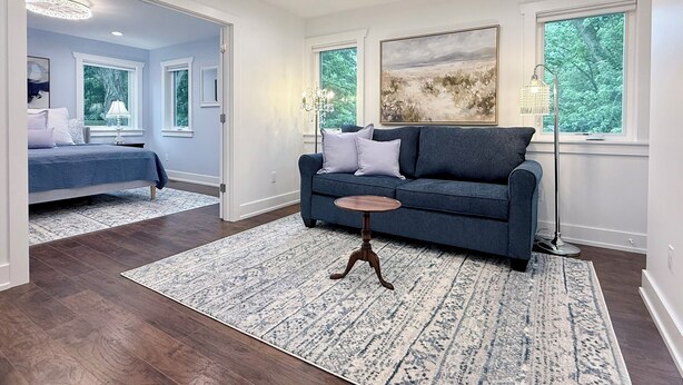 Un salon moderne avec un canapé bleu, une petite table ronde et un grand tableau accroché au mur.