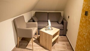 Una habitación pequeña y acogedora con sofá, una silla y una mesa de centro de madera.