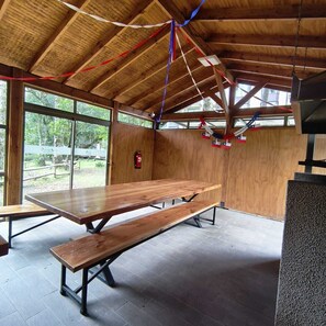 A wooden interior with a long table and benches, large windows, and a fire extinguisher. - Relax in Pucón (Araucanía)
