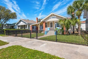 A residential area with houses, a sidewalk, and a black metal fence. - Gorgeous 2-bedroom house near Beach & Cruise Port w/Parking (Galveston)