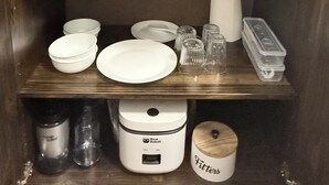 A kitchen area with a microwave, coffee maker, and various kitchen utensils and containers.