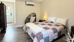 A bedroom with a bed, a chair, a bedside table with a lamp, and a wooden bench.