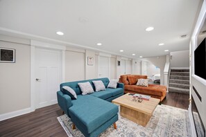 Uma sala de estar moderna com um sofá verde-turquesa, uma mesa de centro de madeira e um tapete estampado.
