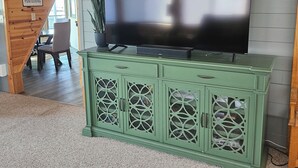 A green cabinet with a television on top, a potted plant, and a sign on the wall.