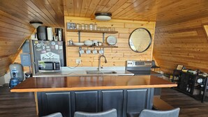 A kitchen with a wooden island, bar stools, a coffee machine, and a mirror on the wall.