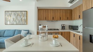 Une cuisine moderne avec des meubles en bois, un plan de travail blanc et un coin repas avec une table dressée pour deux personnes.