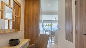 Un intérieur moderne avec un mur lambrissé en bois, un coin salon et une vue sur un balcon aménagé avec du mobilier d’extérieur.