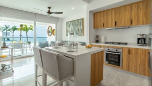 Une cuisine moderne dotée d’un îlot central, de meubles en bois et offrant une vue sur l’océan.