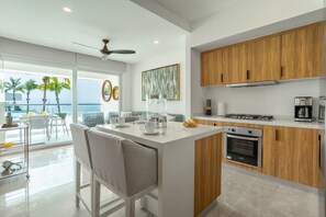 A modern kitchen with a central island, wooden cabinets, and a view of the ocean. - Harbor 171 Beachfront | Walking to the Malecón (Puerto Vallarta)