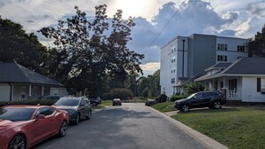Eine Wohnstraße mit parkenden Autos, Häusern und einem mehrstöckigen Gebäude.