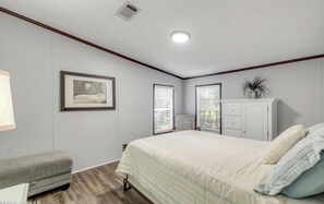 Ein Schlafzimmer mit einem Bett, einer Bank, einem Schrank und einem gerahmten Bild an der Wand.