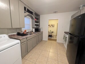 Eine moderne Küche mit grauen Schränken, einem schwarzen Kühlschrank und einer Mikrowelle.